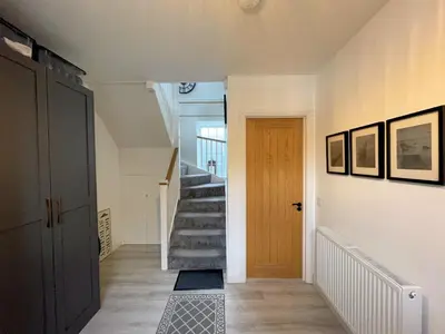 a hallway with a staircase and a wooden door at Stunning Cosy Cottage in Historic Moffat - Pass the Keys in Moffat