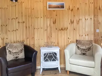 two chairs and a table in a room with wooden walls at Shepherds Cabin - Uk48225 in Ardgour