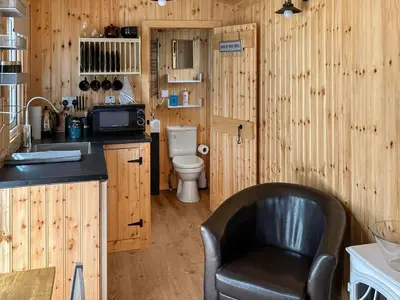 a kitchen with a leather chair and a toilet at Shepherds Cabin - Uk48225 in Ardgour