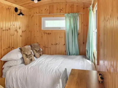 a bedroom with a bed with a table and a window at Shepherds Cabin - Uk48225 in Ardgour