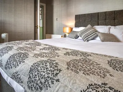 a large bed with a black and white comforter at The Loans Inn Cottage in Loans