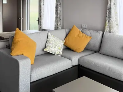 a gray couch with yellow pillows in a living room at Katie's Cosy Caravan - Uk48380 in Ardgour