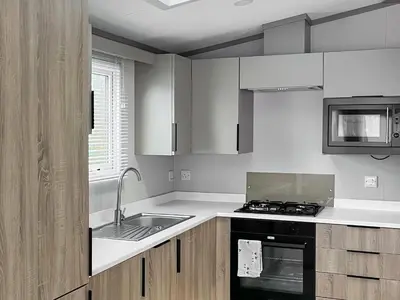 a white kitchen with a sink and a stove at Katie's Cosy Caravan - Uk48380 in Ardgour