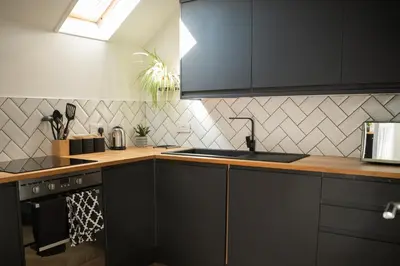 a kitchen with black cabinets and a counter top at Modern apartment with stunning sea views near Oban in Connel