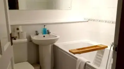 a white bathroom with a sink and a bath tub at Rowantree Cottage in Arrochar