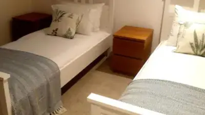 a bedroom with two beds and a night stand at Rowantree Cottage in Arrochar