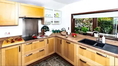 a kitchen with wooden cabinets and a sink and a window at Rowantree Cottage in Arrochar