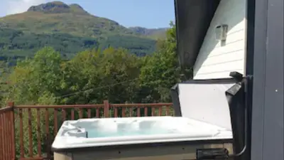 a hot tub on a porch with a view of a mountain at TheLodge in Arrochar