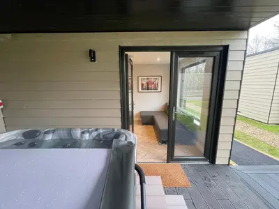 a screened in porch with a hot tub and a sliding glass door at River Logie Lodges in Westfield