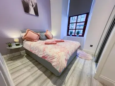 a bedroom with a bed with pink pillows and a window at 2 Bed apartment in city centre! in Glasgow
