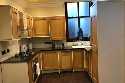 a kitchen with wooden cabinets and a window at 2-Bed Cottage Sleeps 4 10 mins to Glasgow Centre in Glasgow