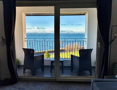 a room with a view of the ocean from a balcony at View of the Isles in Largs