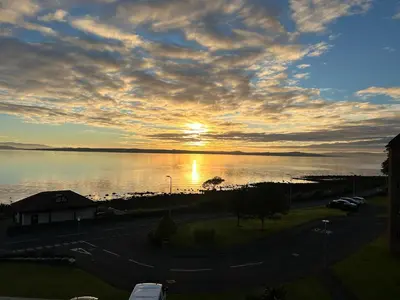 a sunset over a body of water with the sun setting at View of the Isles in Largs