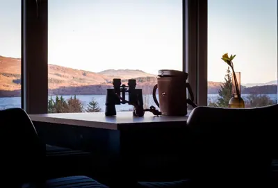 a window with a view of the water and mountains at The Corries B&B in Luss