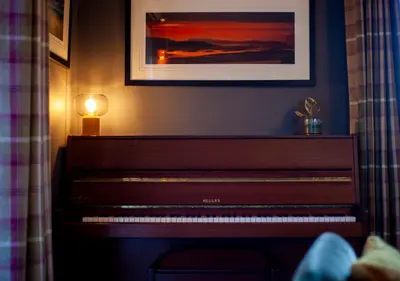 a piano in a room with a picture on the wall at The Corries B&B in Luss