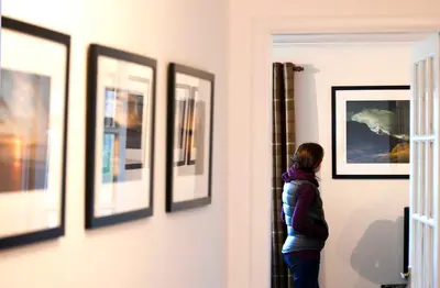 a person looking at art on a wall at The Corries B&B in Luss