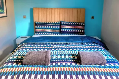 a large bed with two pillows on top of it at Cosy 4 Bedroom Home In Glasgow City - Free Parking in Glasgow