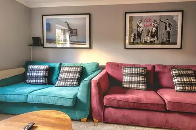 a living room with two couches and a table at Cosy 4 Bedroom Home In Glasgow City - Free Parking in Glasgow