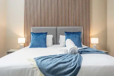 a bedroom with a large bed with blue pillows at The Oliver in Ayr