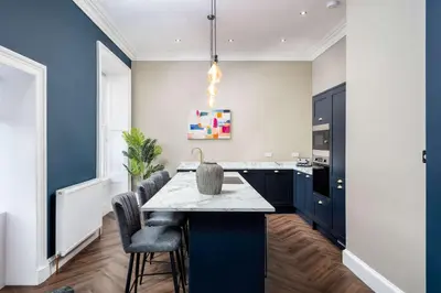 a kitchen with blue cabinets and a table with chairs at The Oliver in Ayr