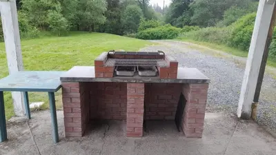 a brick barbecue grill with a bench next to a road at Garlies Lodge in Bargrennan