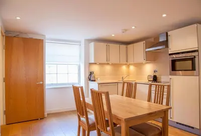 a kitchen with a wooden table and some chairs at CS Exclusive Apartments of Princess Street West End in Edinburgh