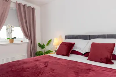 a red and white bed with red pillows in a bedroom at Tranquil Coastal Getaway Home in Saint Davids