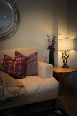 a living room with a couch and a table with a lamp at Am Tighndhuin in Killin