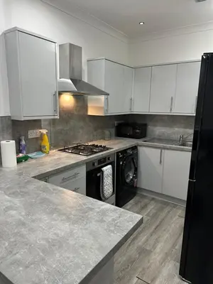 a kitchen with white cabinets and a dishwasher at Cosy Flat in Glasgow