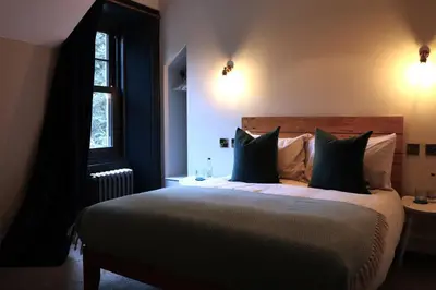 a bedroom with a large bed with black pillows at Suie Hunting Lodge in Killin