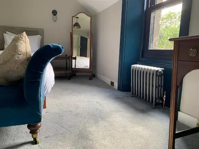 a bedroom with a blue chair and a mirror at Suie Hunting Lodge in Killin