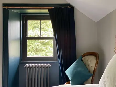 a bedroom with a window and a chair and a radiator at Suie Hunting Lodge in Killin