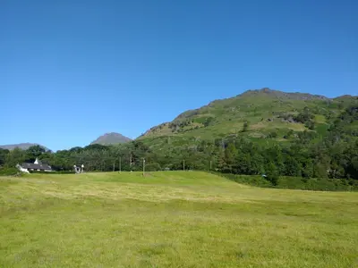 a green field with a mountain in the background at Inveruglas Farm Cottage in Arrochar