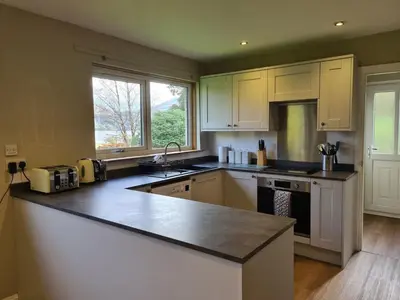 a kitchen with white cabinets and a counter top at Inveruglas Farm Cottage in Arrochar