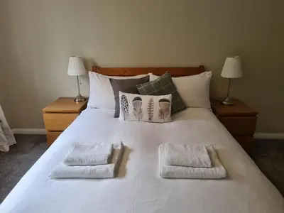 a large white bed with two pillows on it at Inveruglas Farm Cottage in Arrochar