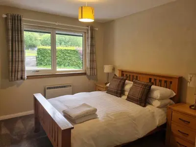 a bedroom with a large bed with a window at Inveruglas Farm Cottage in Arrochar