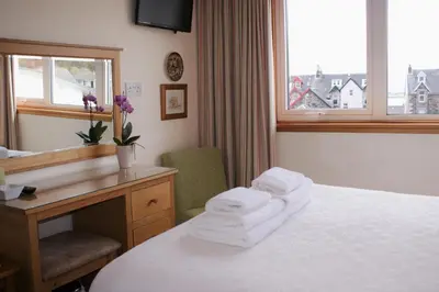 a hotel room with towels on a bed and a desk at Greencourt Guest House in Oban
