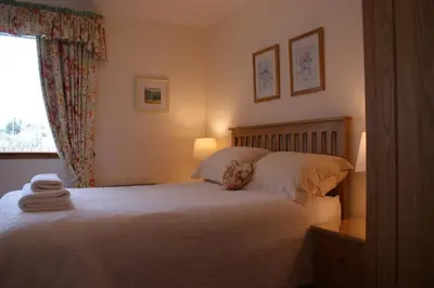 a bedroom with a bed with white sheets and a window at Greencourt Guest House in Oban