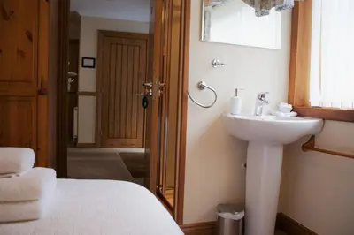 a bathroom with a white sink and a bed at Greencourt Guest House in Oban