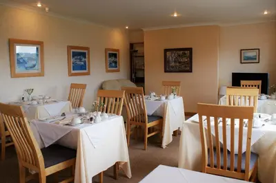 a dining room with tables and chairs with white tablecloths at Greencourt Guest House in Oban