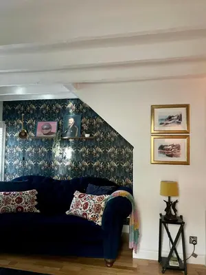 a blue couch in a living room with a wall at Clover Neuk - Hot Tub - Coorie Doon Stays in Fairlie