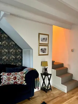 a living room with a blue couch and stairs at Clover Neuk - Hot Tub - Coorie Doon Stays in Fairlie