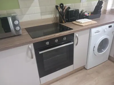 a kitchen with a stove and a washing machine at Douglas Apartment - Trains to Edin & Glasgow - Private Parking in Airdrie