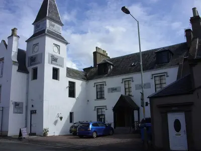 a building with a clock tower and a car parked in front at The Tower Gastro Pub & Apartments in Crieff