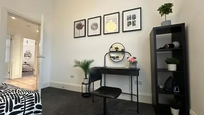 a bedroom with a desk and a mirror on a wall at Bright and spacious apartment near Glasgow in Dalmuir