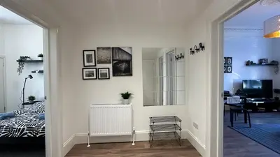 a white living room with a bed and a mirror at Bright and spacious apartment near Glasgow in Dalmuir
