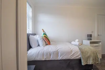 a bedroom with a bed with white sheets and a window at Westlea House in Airdrie