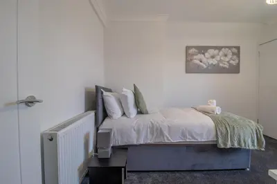a bedroom with a bed with white sheets and pillows at Westlea House in Airdrie