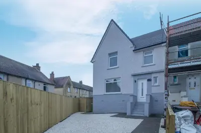 a grey house with a wooden fence in front of it at Westlea House in Airdrie