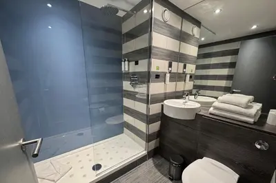 a bathroom with a shower and a toilet and a sink at Village Hotel Glasgow in Glasgow
